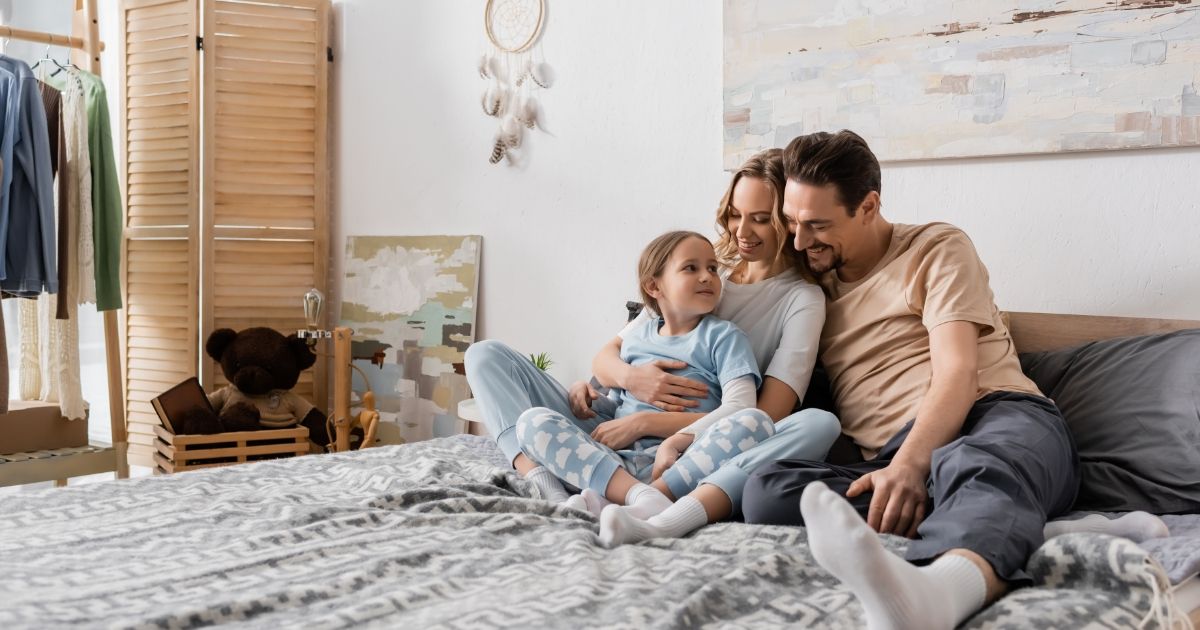 A happy family sitting on a bed, enjoying warmth and comfort, representing Conway, SC Heat Pump Repair