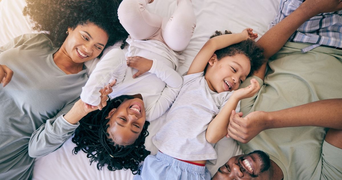 A happy family lying on a bed, enjoying warmth and comfort, representing Conway, SC Emergency Furnace Repair services.