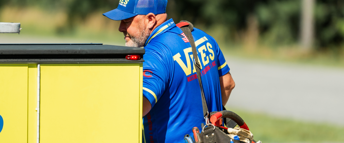 A technician from Vines Restoration holding a red bag working on Ductless Mini Split Maintenance in Myrtle Beach, SC