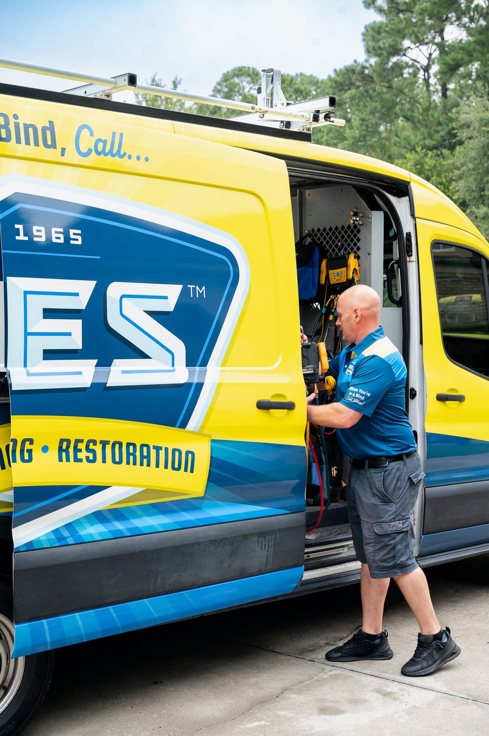 HVAC service technician preparing tools from a van before servicing a heating system.