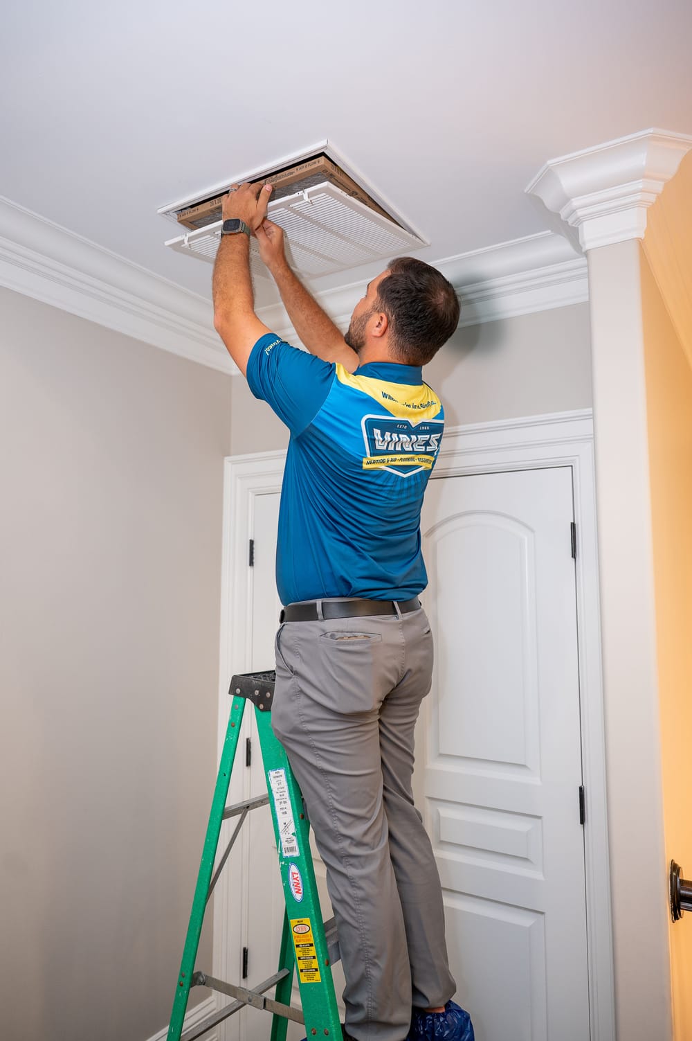 Technician inspecting ceiling air duct opening during duct sealing evaluation inside a home