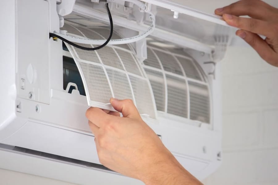 Vines Heating and Air technician inspecting the air filter inside a ductless mini split indoor unit.