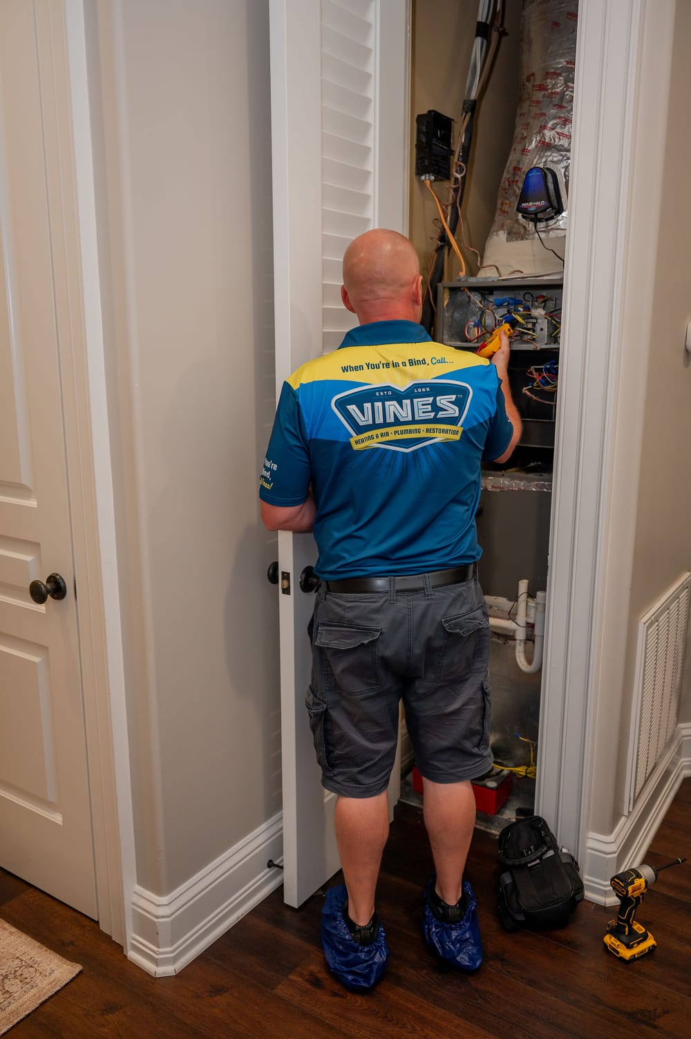 Vines Heating and Air technician inspecting internal components of a residential heating system inside a utility closet.