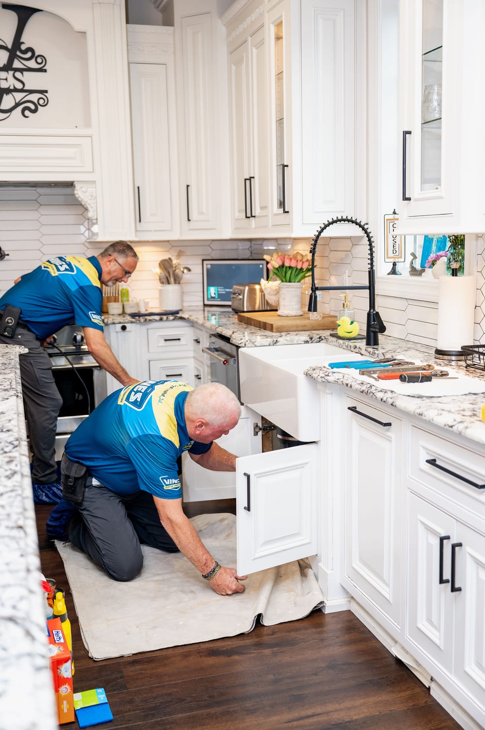 Vines plumbers underneath kitchen sink conducting repairs.