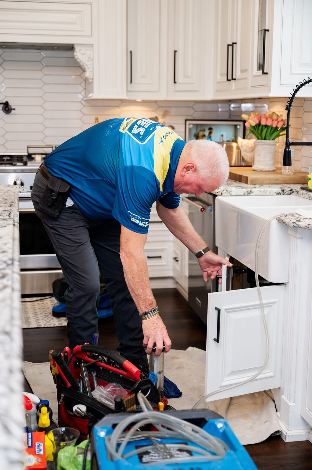 Vines technician conducting water liner repairs under sink.