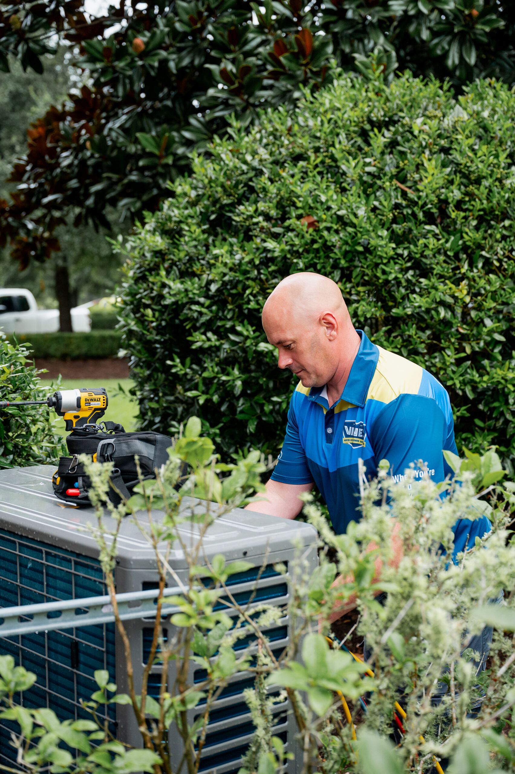 HVAC technician in a blue work shirt is servicing an outdoor AC unit