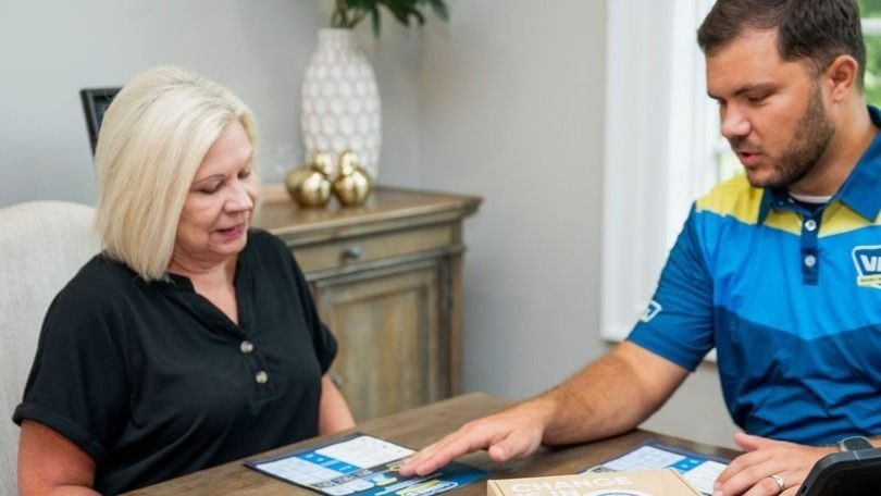 HVAC technician showing a customer how the Smart Alex works. They are sitting at a table in the customer's home.